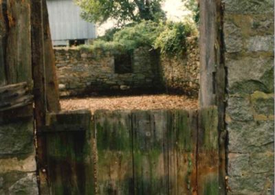 View through door into old dairy barn foundation. Bank barn is visible in the background.